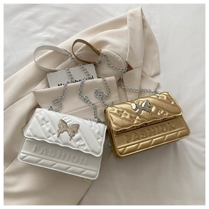 Detailed close-up of quilted chain bags in white and champagne gold with butterfly clasps