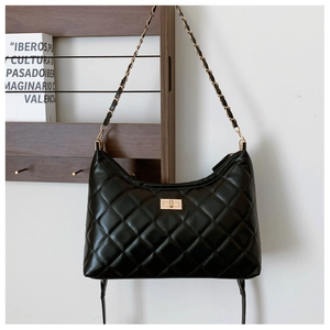 Detail of black quilted leather shoulder bag with gold chain strap and twist-lock clasp