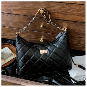 Close-up of quilted leather texture and gold metal twist lock on a black tote bag
