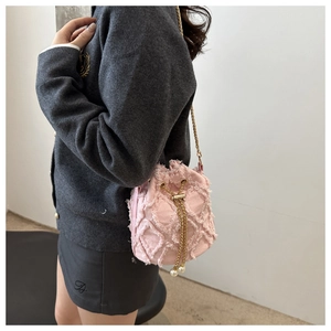 Detail showing pink denim bucket bag with frayed edges and pearl chain shoulder strap