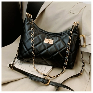 Detail of classic black quilted tote bag with gold rotary lock and metal chain strap
