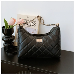 Detailed close-up of a black quilted hobo bag with gold hardware on a wooden table