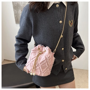 Detail of pink tweed bucket bag featuring raw edges, pearl accents, and gold chain strap