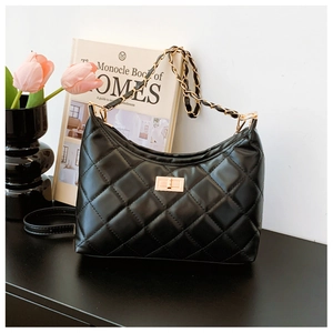 Close-up of black quilted tote bag with gold chain strap and elegant twist lock