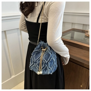 Detail of denim bucket bag showing raw edge diamond pattern and pearl drawstring closure