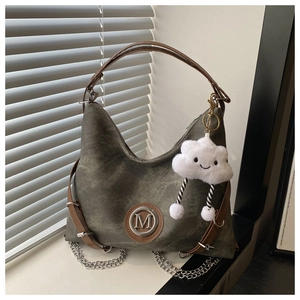 Detail of olive green hobo bag with leather handles and a plush cloud charm