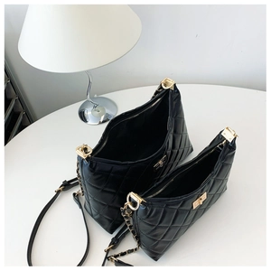 Set of two black quilted tote bags with gold chain straps on a white table display