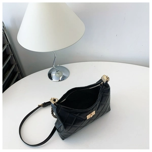Detailed top view of black quilted tote bag with golden twist lock and chain strap