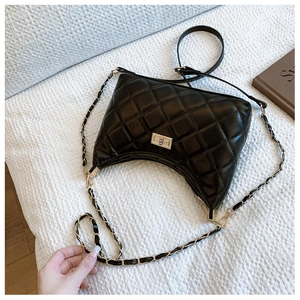 Detail of black quilted hobo bag featuring golden twist lock and chain strap on knit surface