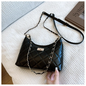 Detail of black quilted leather tote bag with gold chain strap and turn-lock closure