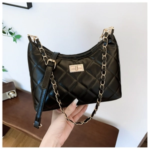 Detail of black quilted leather shoulder bag with gold chain strap and metal clasp