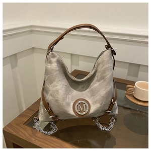Detail of gray washed canvas crossbody bag with brown leather handles and M logo