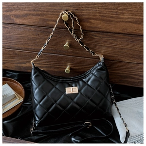 Detailed view of quilted black tote bag with gold hardware on vintage wooden handle