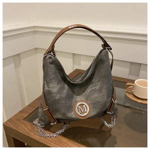 Detail of vintage canvas tote with brown leather handles and metallic M logo