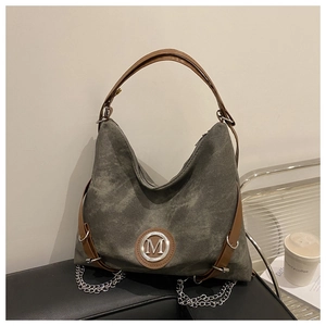 Detail of vintage canvas tote with brown leather handles and decorative metal chain