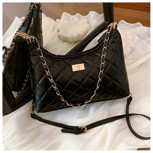 Detail of black quilted shoulder bag with gold chain strap and metallic twist lock clasp