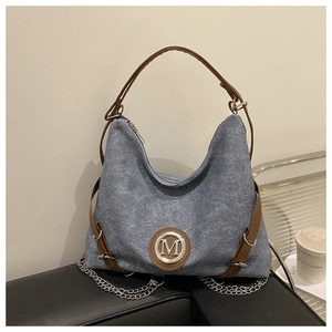 Detail of blue denim hobo bag with brown leather strap and silver chain accent