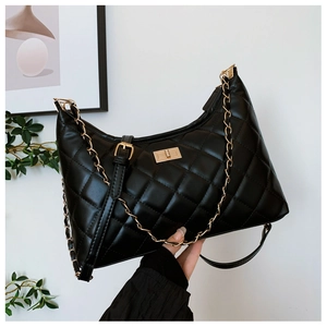 Detail of black quilted leather shoulder bag with gold metal twist lock and chain strap