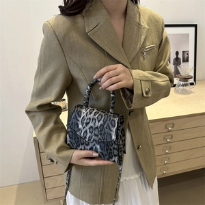 Retro leopard print crossbody bag with magnetic closure held by model in neutral suit