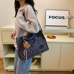Stylish purple leopard print tote bag with wide strap and plush bear charm accent