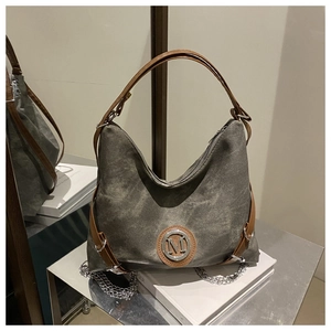 Detail view of canvas tote bag with brown leather straps and metal chain decoration