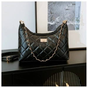 Detail of black quilted hobo bag with gold chain strap and turn-lock on a side cabinet