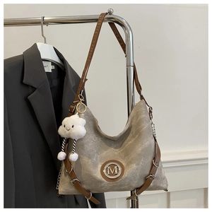 Détail du sac cabas vintage gris avec logo M et charme nuage suspendu sur un portant