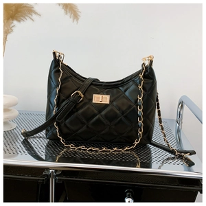 Detail of black quilted tote bag featuring golden twist lock and chain strap on silver cart