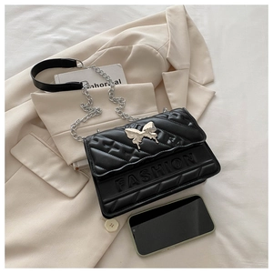 Detail of quilted leather black handbag featuring a silver butterfly clasp and chain strap