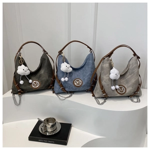 Détail des sacs cabas en vert, bleu denim et gris avec logo M et pendentifs en peluche