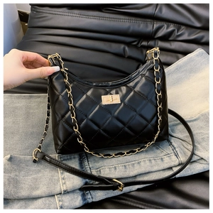 Detail of quilted black tote bag featuring gold chain handle and twist-lock clasp