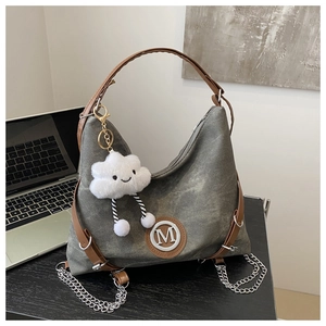 Close-up of grey canvas tote bag with brown leather handles and plush cloud charm