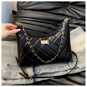 Detail of black quilted shoulder bag featuring gold chain and metallic buckle closure