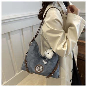 Detail of grey canvas hobo bag with brown leather strap and cloud charm on a model