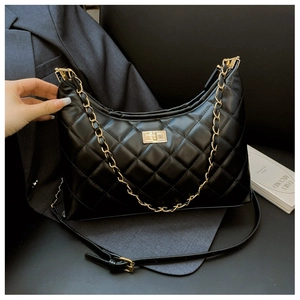 Close-up of black quilted hobo bag with gold metal twist lock and chain strap detail