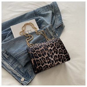 Detailansicht der Umhängetasche mit Leopardenmuster und goldener Perlenkette auf Denim