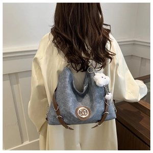 Vue détaillée du sac gris avec bandoulière en cuir marron et pendentif nuage blanc