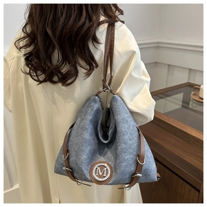 Close-up of grey felt tote bag with leather straps and silver M logo on a model