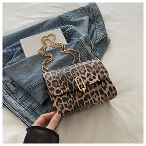 Detail of leopard print flap bag featuring a gold oval clasp and beaded metal chain strap