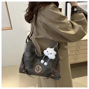 Sac en toile grise avec bordures en cuir et charme nuage pelucheux sur l'épaule du modèle