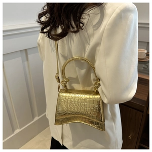 Detail of golden crocodile pattern hourglass bag with a stylish knot handle and strap