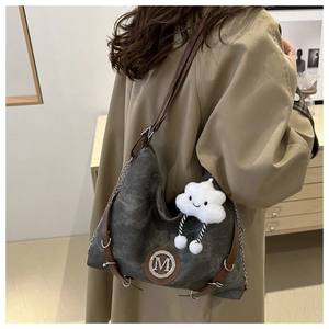 Vue détaillée d'un sac en toile grise avec bandoulière en cuir et charm peluche nuage