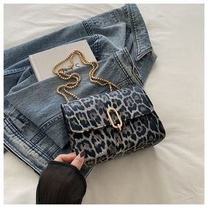 Detail shot of leopard print shoulder bag with gold chain strap on soft white bedding