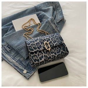 Detail der Handtasche mit Leopardenmuster, goldener U-Schnalle und feinem Metallkettenriemen