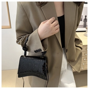 Detail of black faux crocodile patent leather mini bag with unique knotted handle design