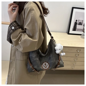 Detail of dark grey canvas hobo bag with leather trim and plush cloud pendant charm