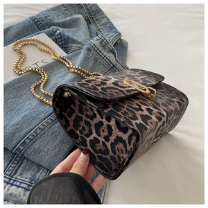 Detail der Leoparden-Handtasche mit goldener Kugelkette auf einer Jeansjacke