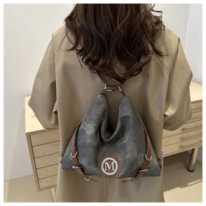 Detail of vintage washed canvas crossbody bag with silver M logo and leather straps