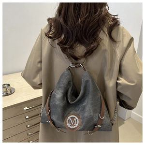 Detail view of the large grey tote bag worn as a backpack with brown leather accents