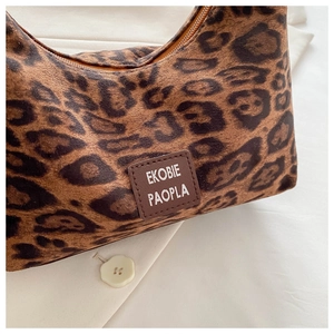 Gros plan du sac en peluche léopard avec patch logo en cuir et détails de zip métallique